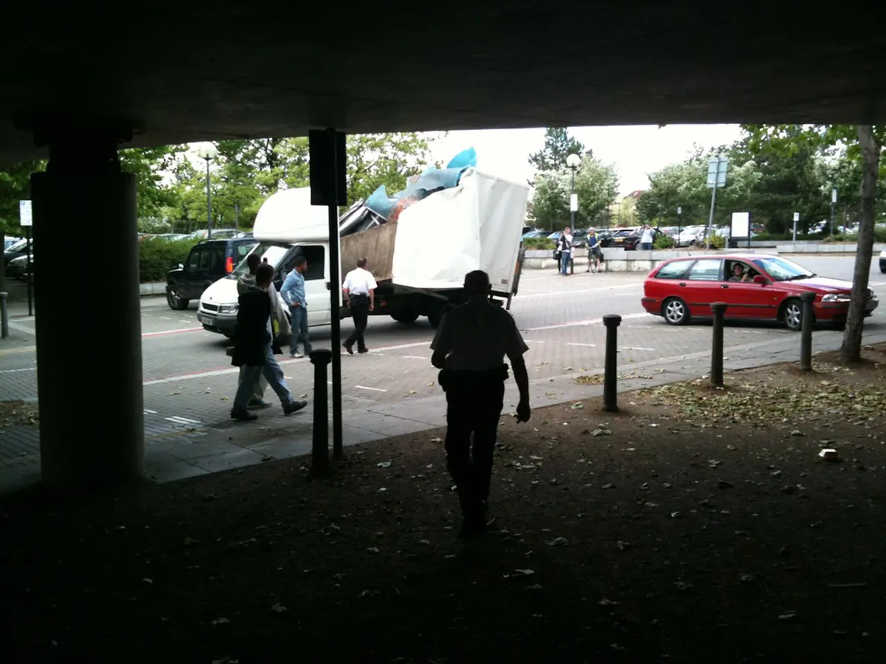 There are so many people walking and there is a car and truck on road.