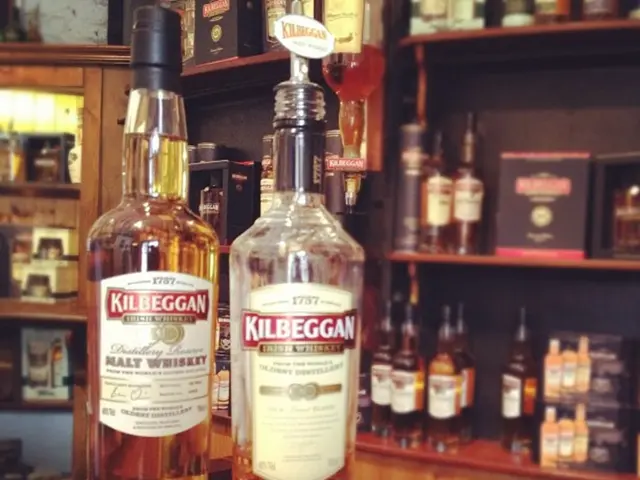 On the table there are two bottles with the label on it. In the background there are cupboards with...