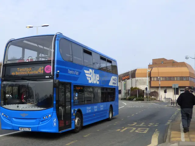 In this image in the center there is a bus which is blue in colour with some text written on it...