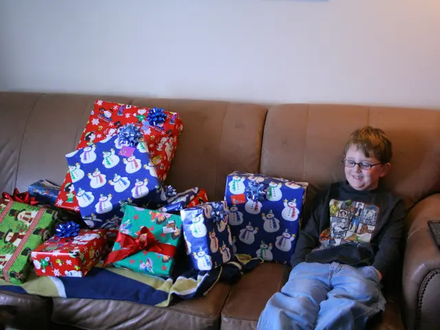 In this image there is a person sitting on the sofa. On the sofa there are so many gifts and a...