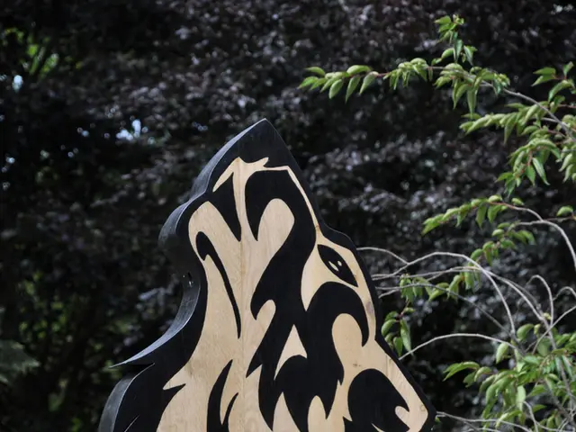 This picture shows trees and a metal fence and we see a painting on the wood.