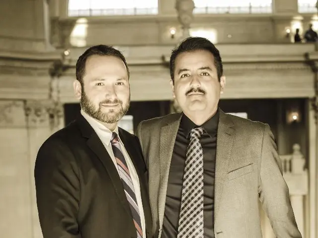 In this image we can see two men are standing at the fence. In the background we can see lights,...