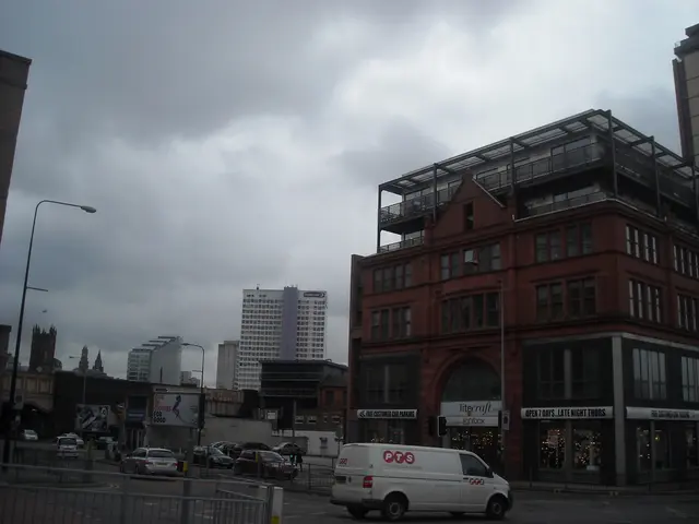 In this image I can see few buildings, windows, fencing, light poles, traffic signals, boards, sky...